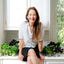 Photo of Dress It Up Dressing Founder Sophia Maroon sitting on kitchen counter surrounded by fresh lettuce
